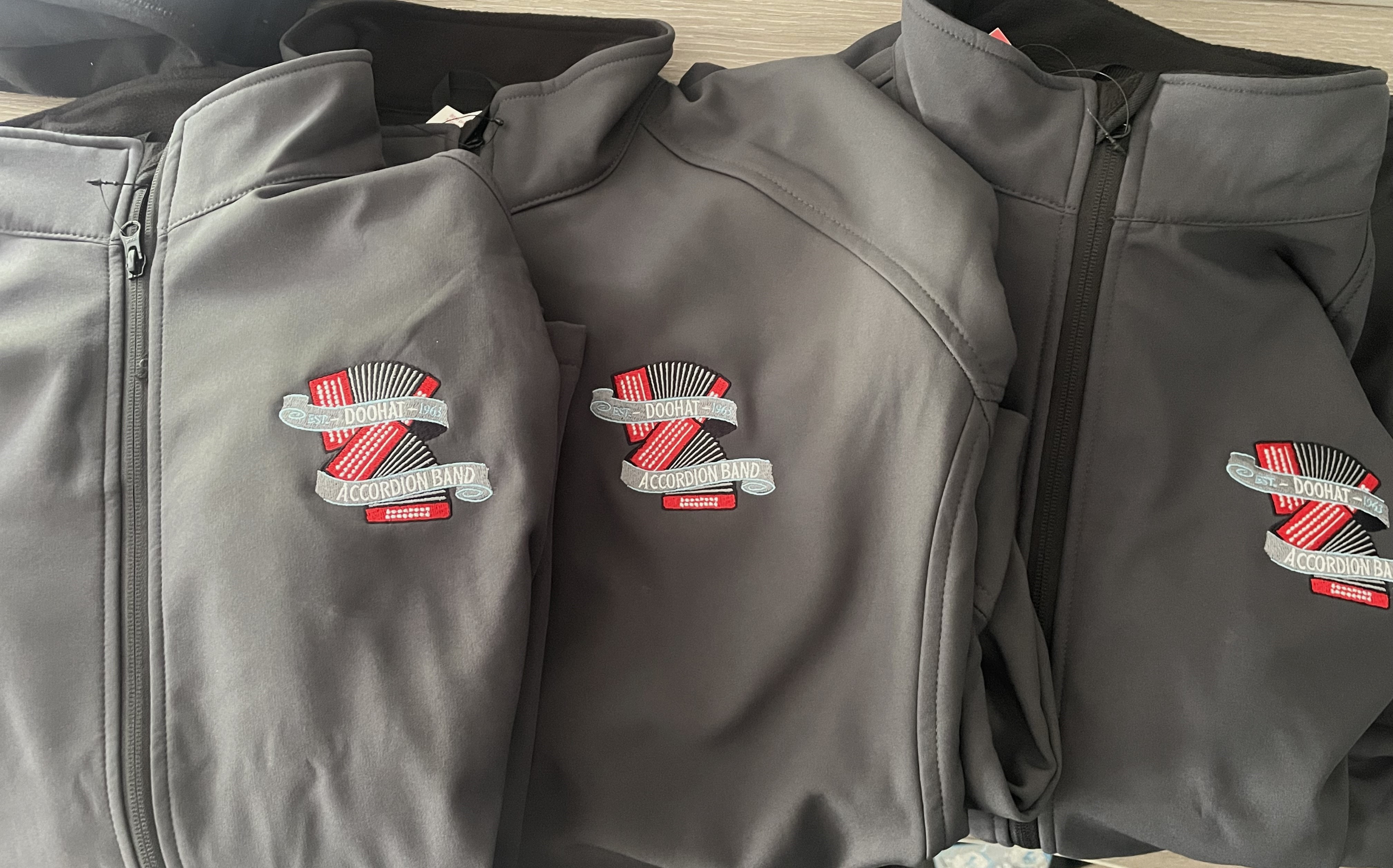 Three grey full zip jackets with the Doohat Accordion Band logo over the left chest.