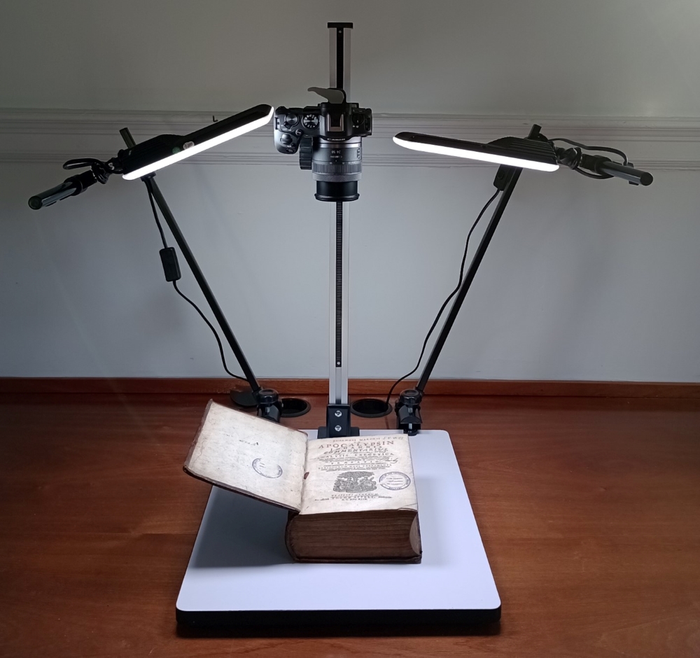 Digital camera on a stand with lighting above an old hardback book.